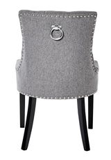 Rückansicht eines grauen Stuhls mit Nietenverzierung und einem dekorativen Metallring an der Rückenlehne, schwarze Beine.