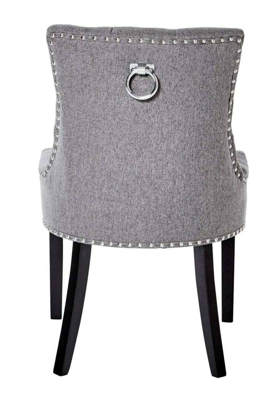 Rückansicht eines grauen Stuhls mit Nietenverzierung und einem dekorativen Metallring an der Rückenlehne, schwarze Beine.