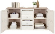 Frontale Ansicht des Hom'in Sideboards CAMRON mit offenen Türen und Schubladen, dekoriert mit Büchern, Pflanzen und gefalteter Kleidung.