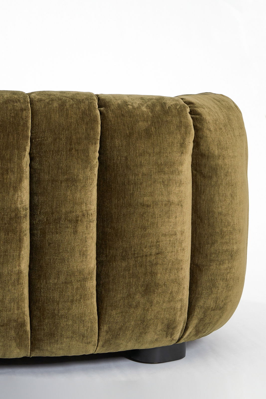 Nahaufnahme einer olivgrünen Couch mit weichem, gepolstertem Stoff und vertikalen Nähten, seitliche Perspektive