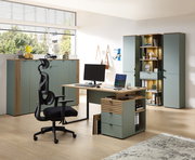 Moderne Büroeinrichtung mit Schreibtisch, ergonomischem Stuhl und mehreren Büroschränken in einem hellen Raum mit großen Fenstern, seitliche Perspektive.