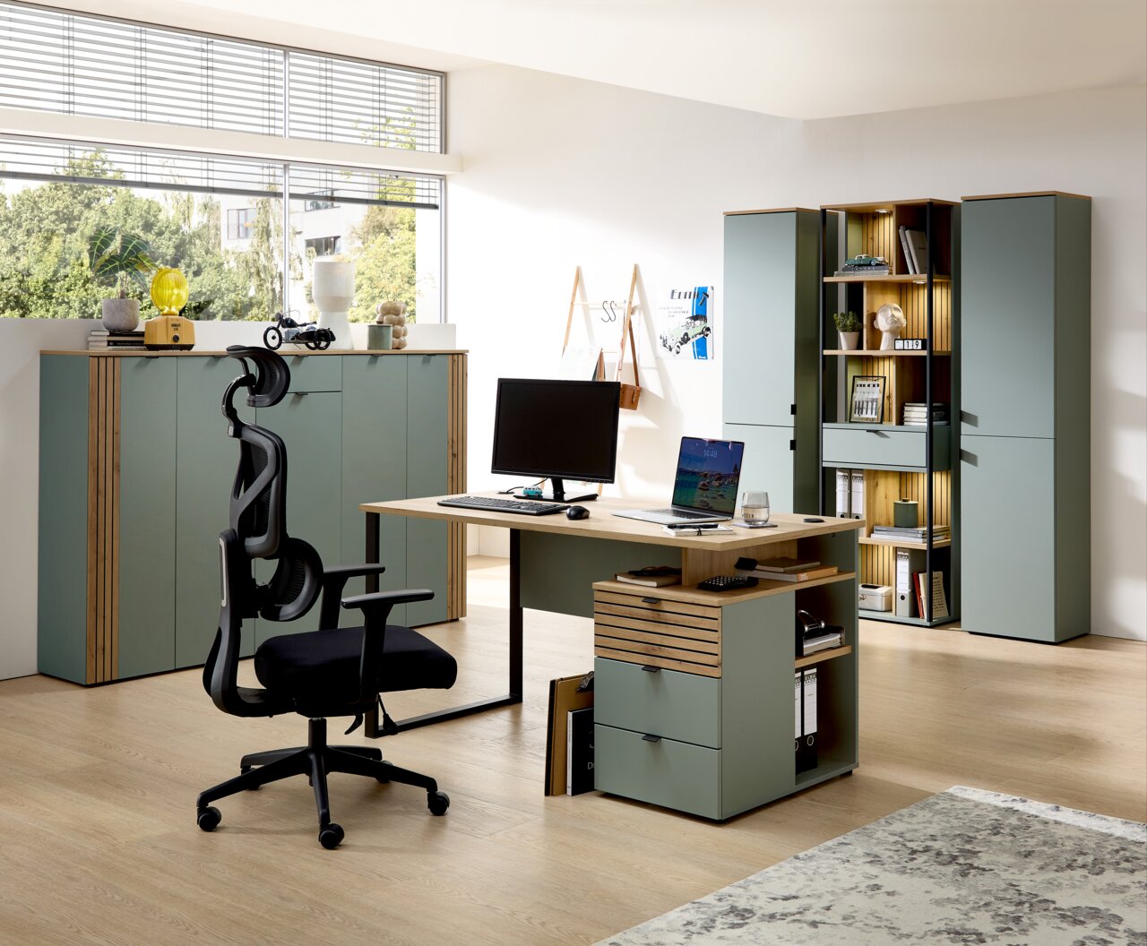 Moderne Büroeinrichtung mit Schreibtisch, ergonomischem Stuhl und mehreren Büroschränken in einem hellen Raum mit großen Fenstern, seitliche Perspektive.