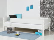 Weißes Kinderbett mit 3/4 Absturzsicherung, seitliche Perspektive, dekoriert mit Kissen und Spielzeug auf einem blauen Teppich.