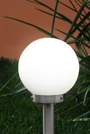 Außen-Stehleuchte NISIA mit kugelförmigem Leuchtkörper auf einem Metallpfosten, seitliche Perspektive im Garten