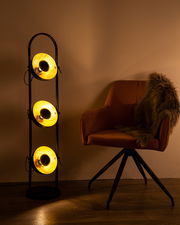 Stehleuchte OLENOW mit drei leuchtenden Lampenschirmen in einem modernen Wohnzimmer, seitliche Perspektive.