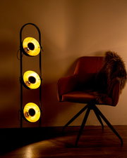 Stehleuchte OLENOW mit drei leuchtenden Lampenschirmen in einem modernen Wohnzimmer, seitliche Perspektive.