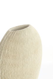 Nahaufnahme einer cremefarbenen Vase mit geriffelter Textur, seitliche Perspektive