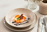 Elegantes Tellerset 18-tlg in natürlichem Beige-Ton, präsentiert mit kunstvoll angerichtetem Gericht, seitliche Perspektive.