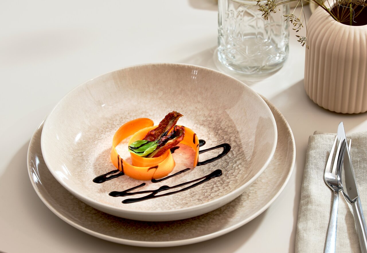 Elegantes Tellerset 18-tlg in natürlichem Beige-Ton, präsentiert mit kunstvoll angerichtetem Gericht, seitliche Perspektive.