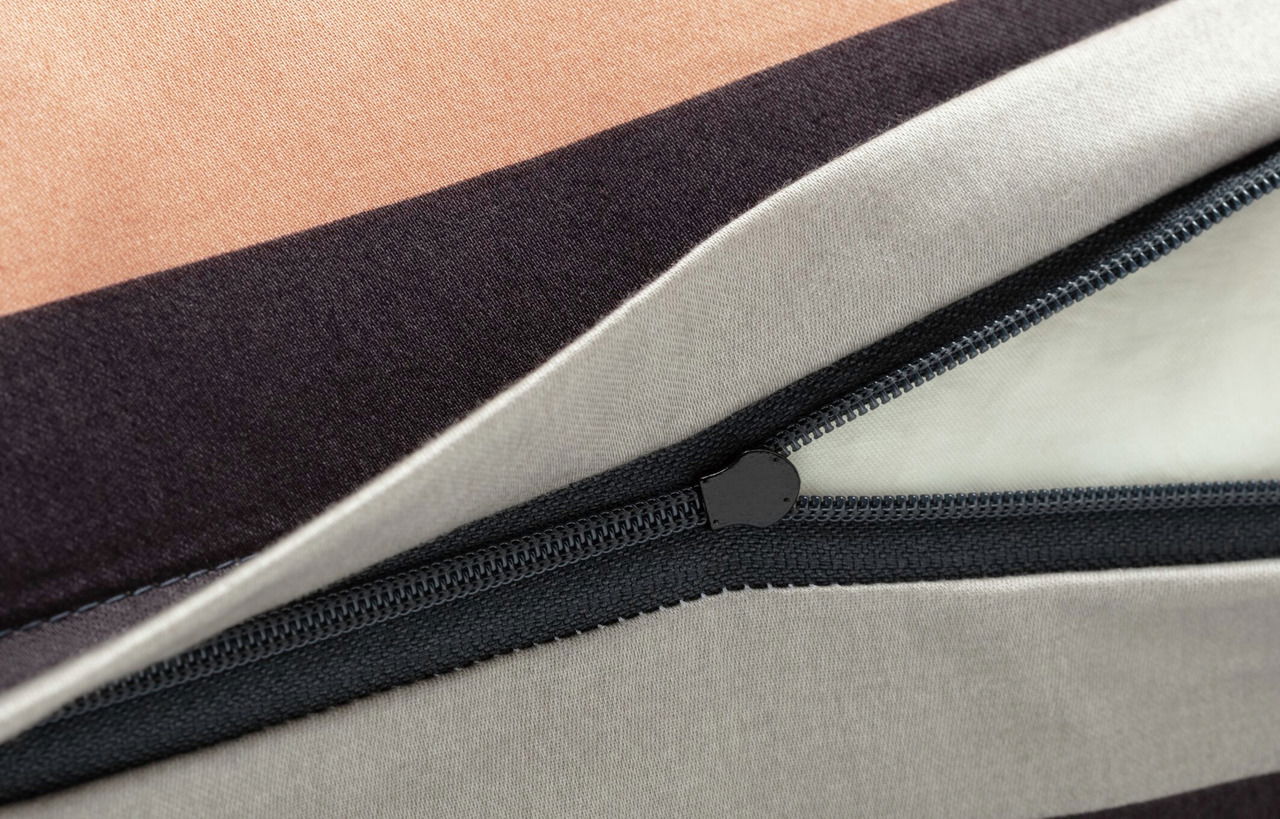 Nahaufnahme einer Bettwäsche mit Reißverschluss, in Streifen aus Beige, Schwarz und Grau.