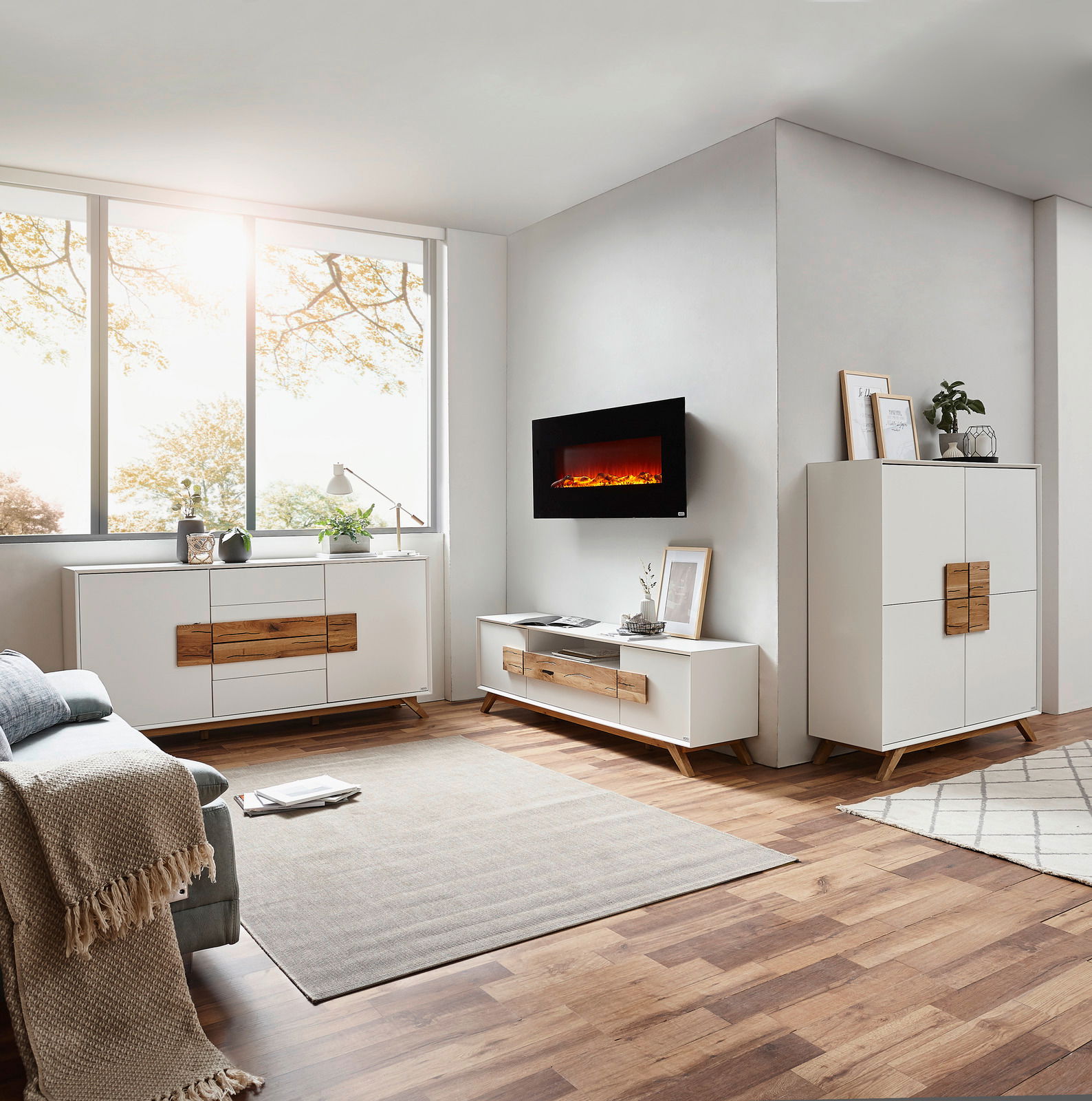 Modernes Wohnzimmer mit Elektrokamin, Sideboard und Highboard in heller Holzoptik, seitliche Perspektive