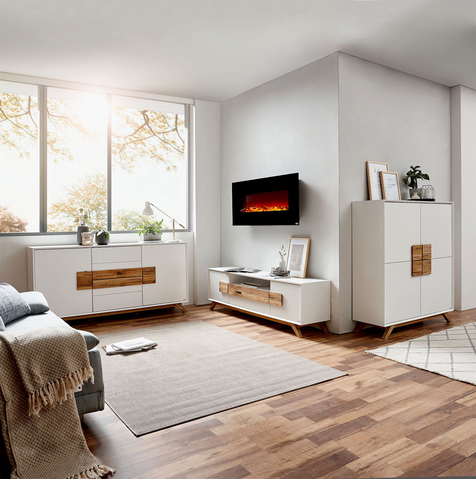 Modernes Wohnzimmer mit Elektrokamin, Sideboard und Highboard in heller Holzoptik, seitliche Perspektive