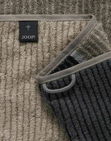 Nahaufnahme eines gestreiften Gästetuchs in verschiedenen Grautönen mit einem Joop-Label.