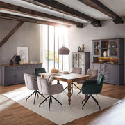 Esszimmer mit Holztisch und gepolsterten Stühlen, umgeben von grauen Sideboards und Highboard, seitliche Perspektive