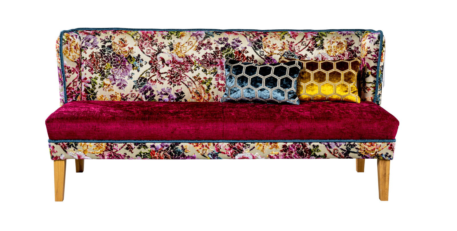 Frontansicht eines farbenfrohen 2-Sitzer-Sofas mit floral gemusterter Rückenlehne, bordeauxroter Samt-Sitzfläche, zwei Zierkissen (Wabenmuster in Blau und Gold) und Holzbeinen vor weißem Hintergrund