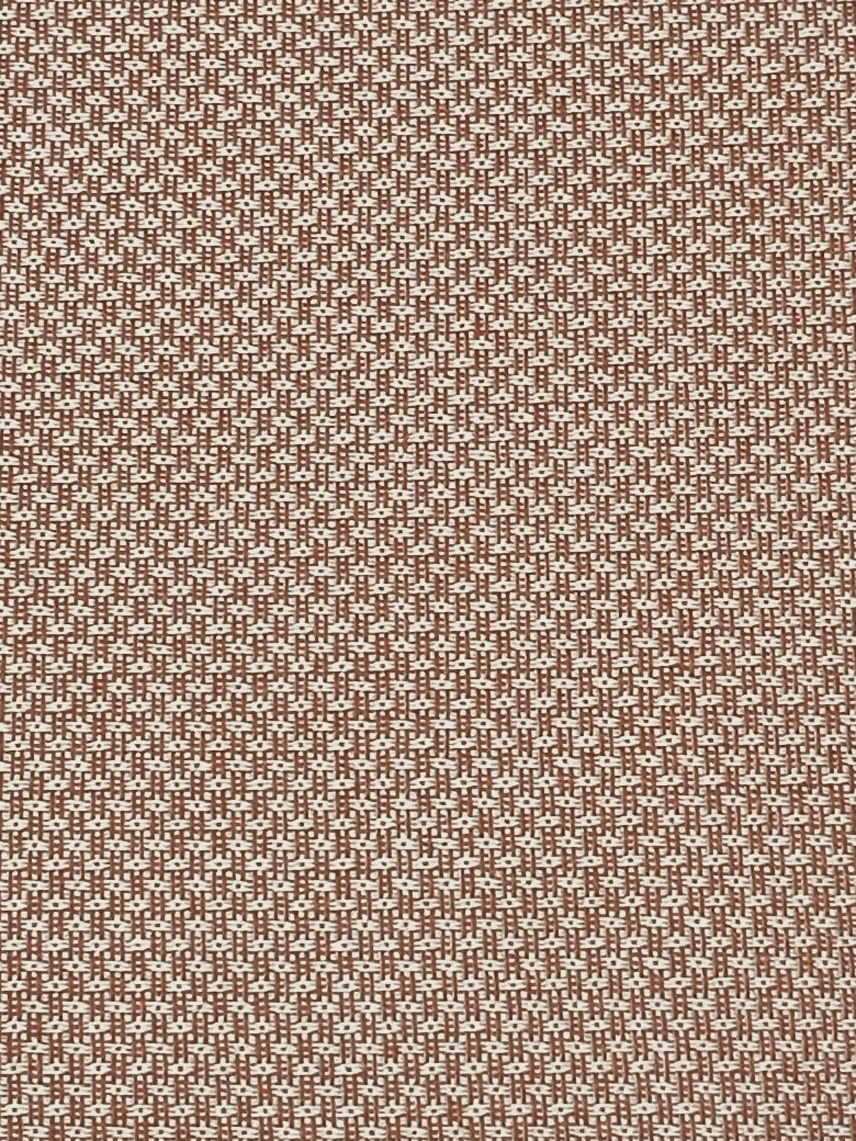 Nahaufnahme eines braun-weiß gemusterten Stoffes in einer gewebten Struktur, von oben betrachtet.
