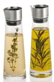 Zwei Glasflaschen mit Edelstahlverschluss, gefüllt mit Essig und Öl, jeweils mit Kräutern, aus frontaler Perspektive.