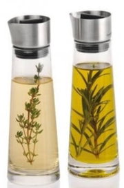 Zwei Glasflaschen mit Edelstahlverschluss, gefüllt mit Essig und Öl, jeweils mit Kräutern, aus frontaler Perspektive.