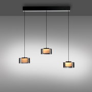 Drei moderne Pendelleuchten RIKA mit zylindrischen, transparenten Schirmen und warmem Licht, von vorne betrachtet.