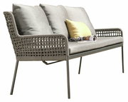 Seitliche Ansicht einer modernen Dining Bank mit grauem Geflecht und Kissen, dekoriert mit einem gelben Kissen und einer Zeitschrift.