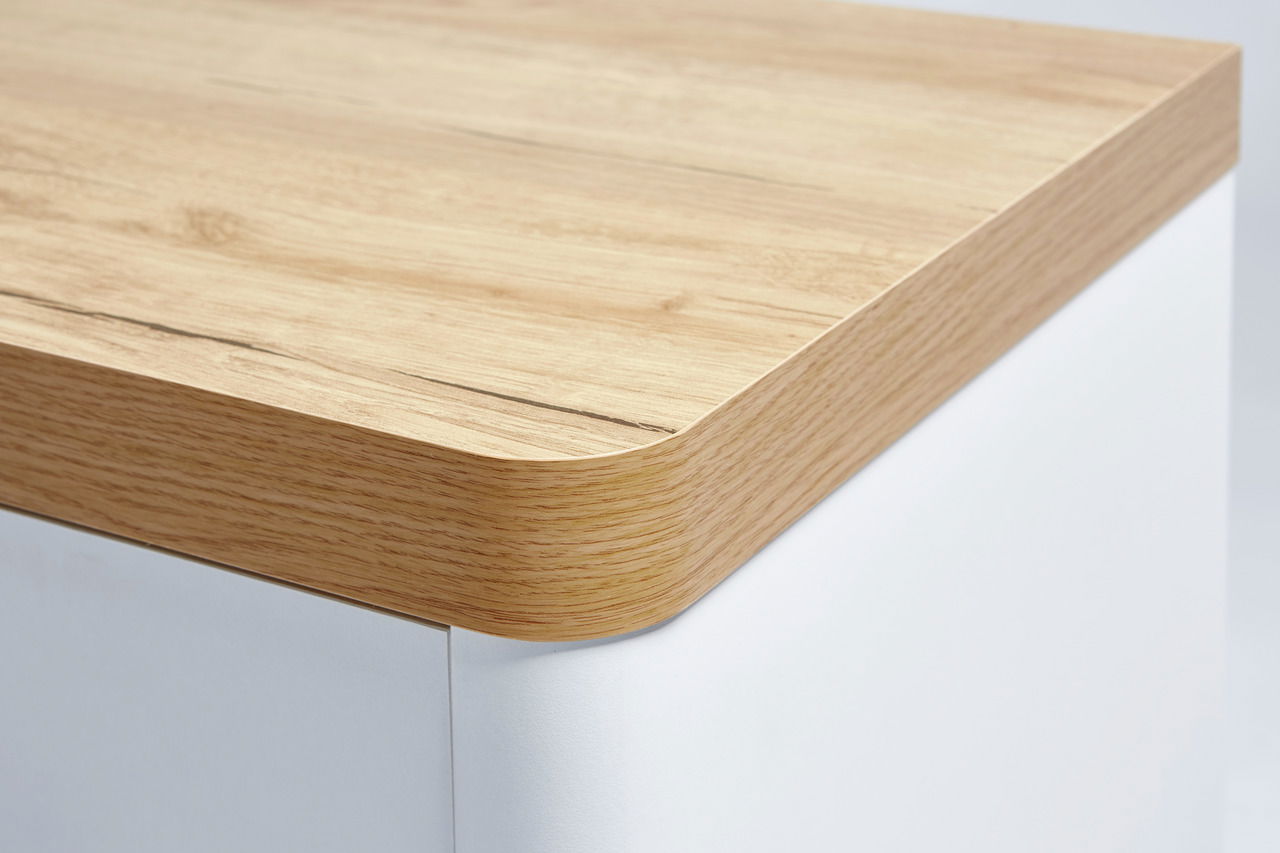 Nahaufnahme einer Schreibtischecke mit abgerundeter Holzkante und weißem Korpus, Perspektive von oben.