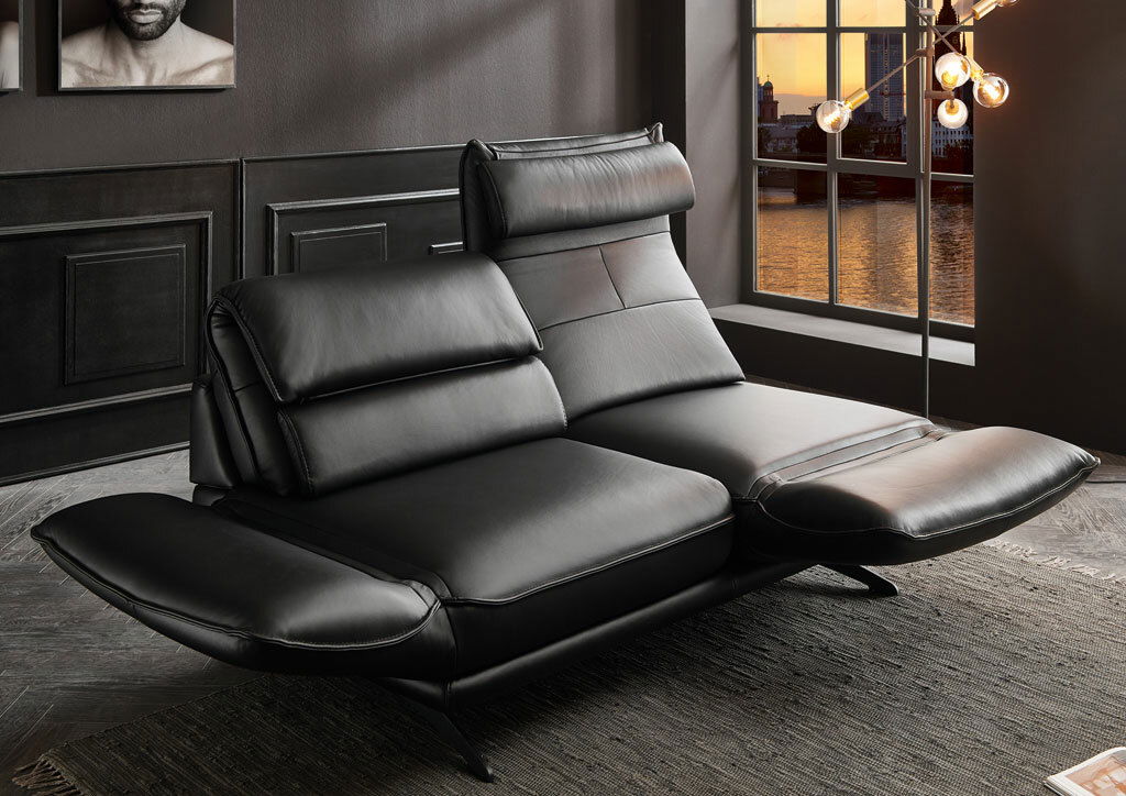 Modernes schwarzes Ledersofa in einem stilvollen Raum mit Blick auf ein Fenster bei Sonnenuntergang, seitliche Perspektive.