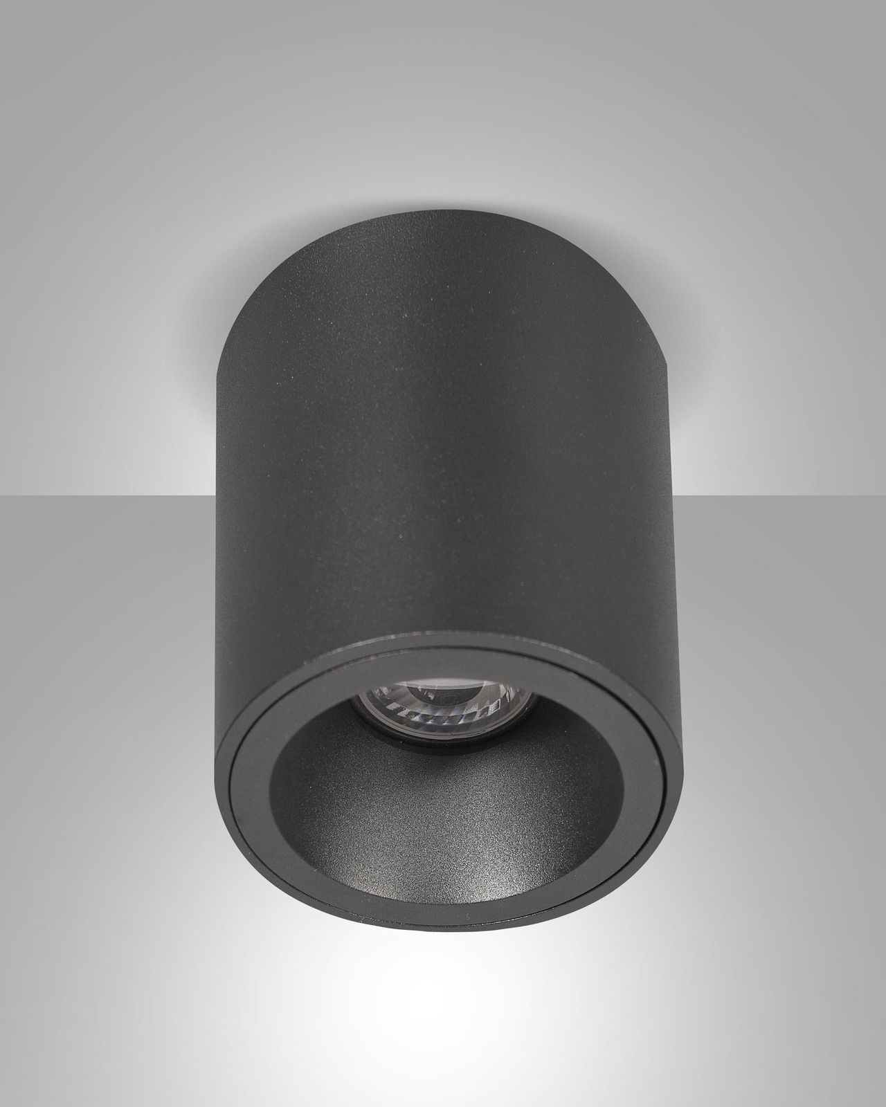 Zylindrischer schwarzer Aufbauspot von unten betrachtet, montiert an der Decke.