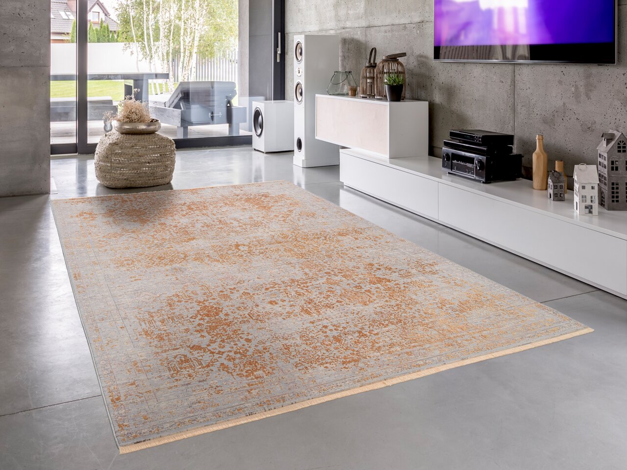 Designer Teppich in einem modernen Wohnzimmer, mit einem eleganten Muster in warmen Erdtönen, auf einer Betonbodenfläche, seitliche Perspektive.