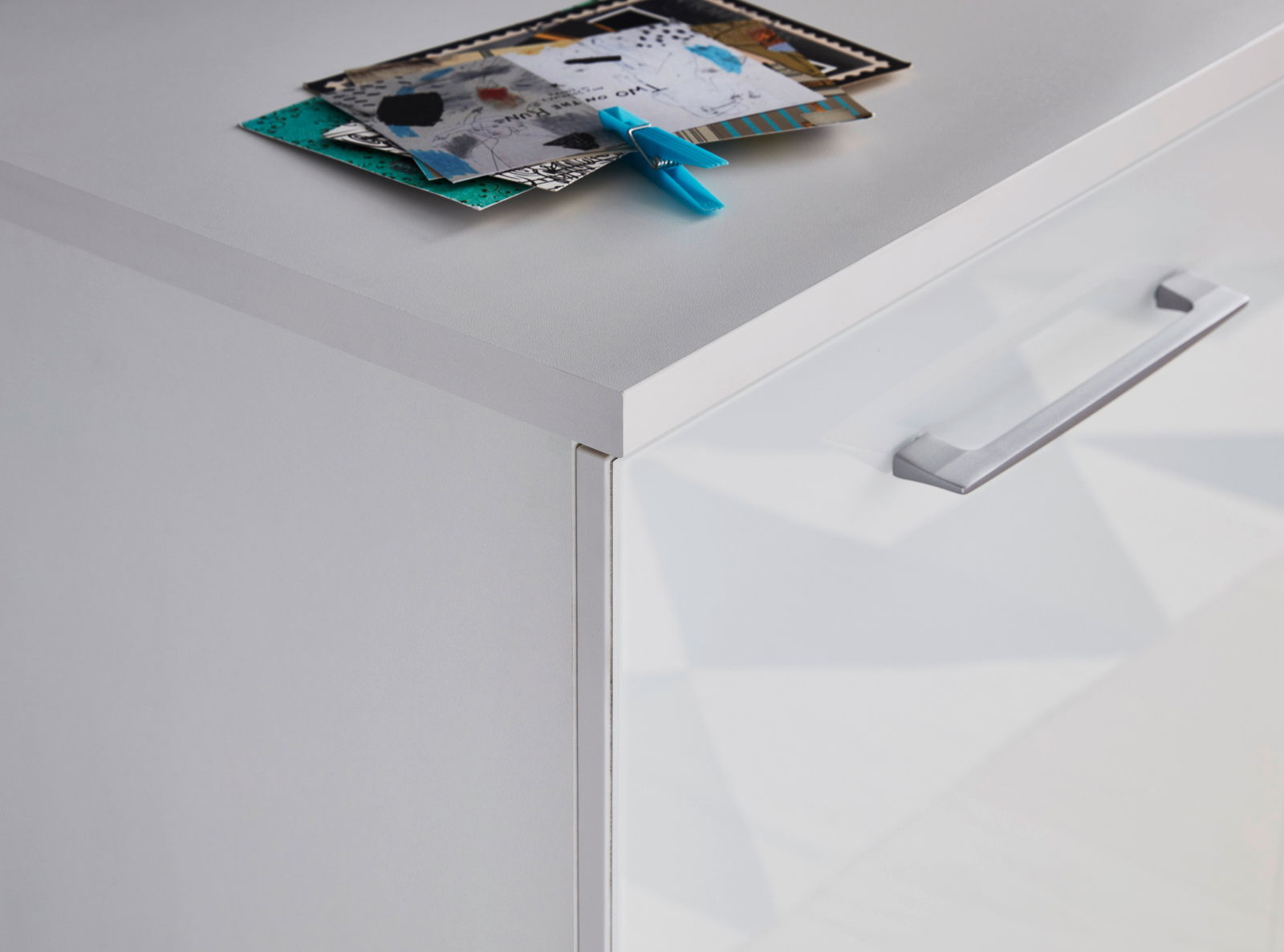 Nahaufnahme einer weißen Kommode mit glatter Oberfläche und modernem Griff, von oben betrachtet.