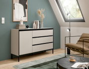 Modernes Sideboard in einem stilvollen Raum mit schrägem Dachfenster, dekoriert mit Kunstobjekten und Büchern, seitliche Perspektive.