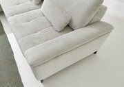 Nahaufnahme eines modernen Ecksofas mit hellgrauem, geripptem Stoffbezug. Die Perspektive zeigt die Armlehne und Sitzfläche von oben.