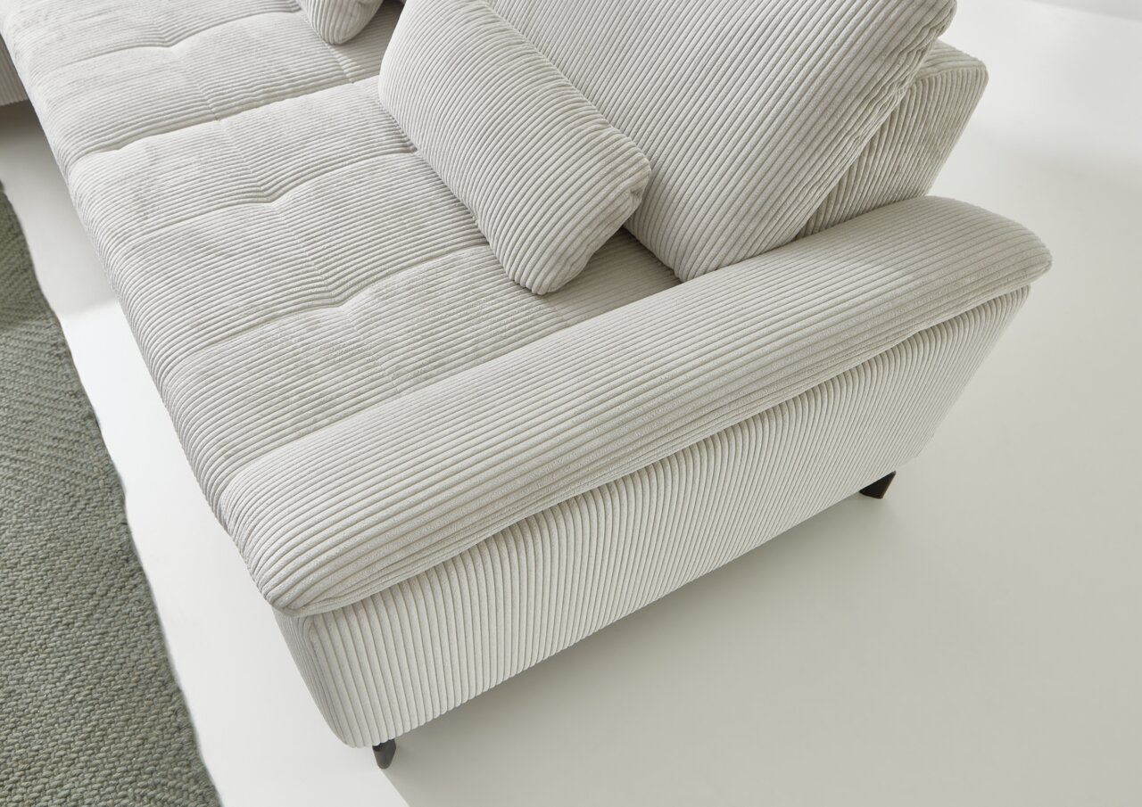 Nahaufnahme eines modernen Ecksofas mit hellgrauem, geripptem Stoffbezug. Die Perspektive zeigt die Armlehne und Sitzfläche von oben.