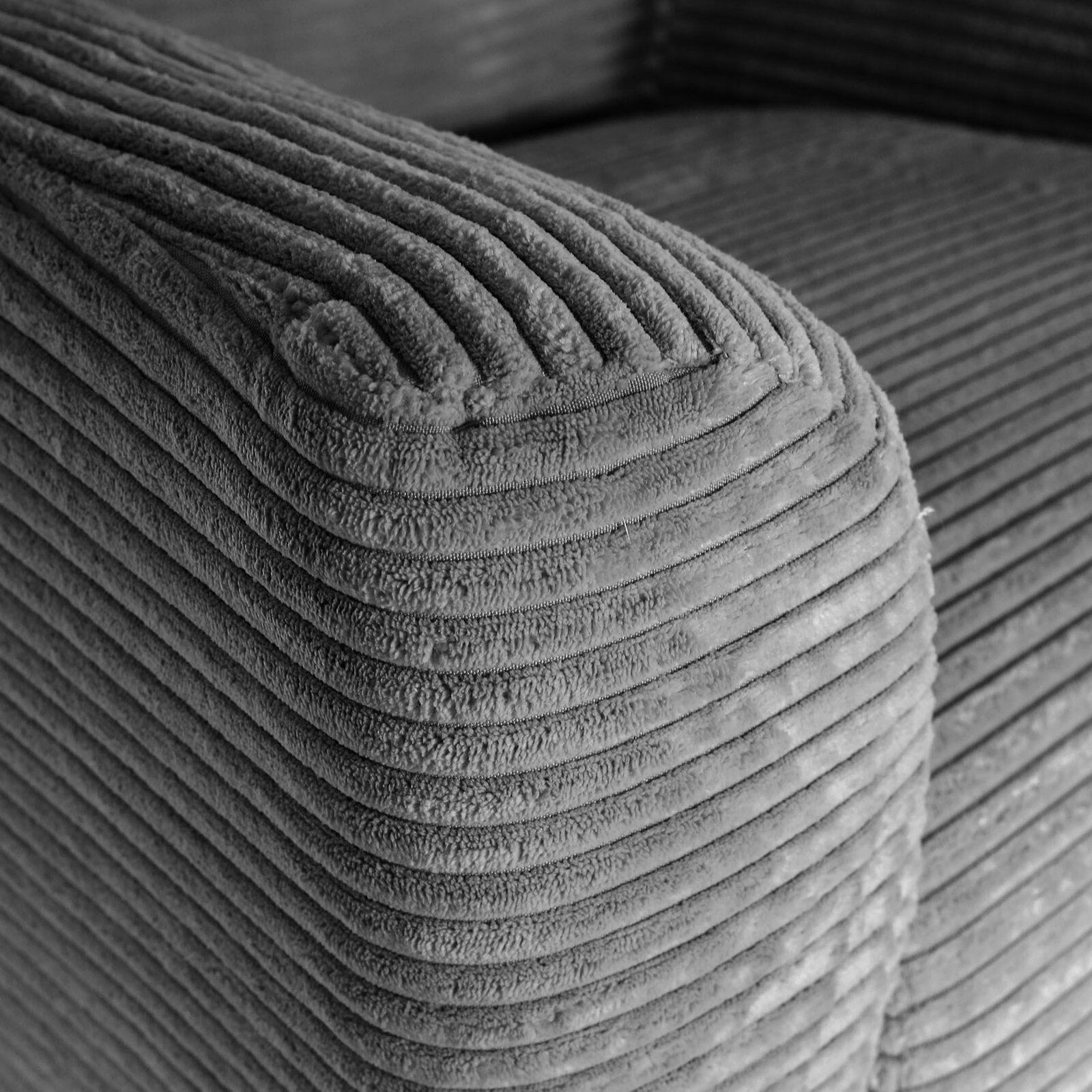 Nahaufnahme einer gerippten Cord-Polsterung an der abgerundeten Ecke eines Sofas, schräg von oben fotografiert