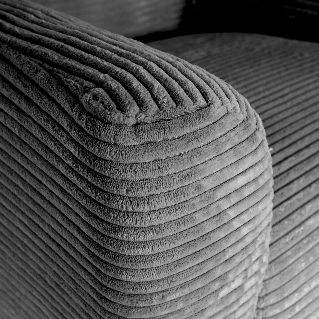 Close-up van een geribbelde corduroy bekleding op de afgeronde hoek van een bank, schuin van bovenaf gefotografeerd