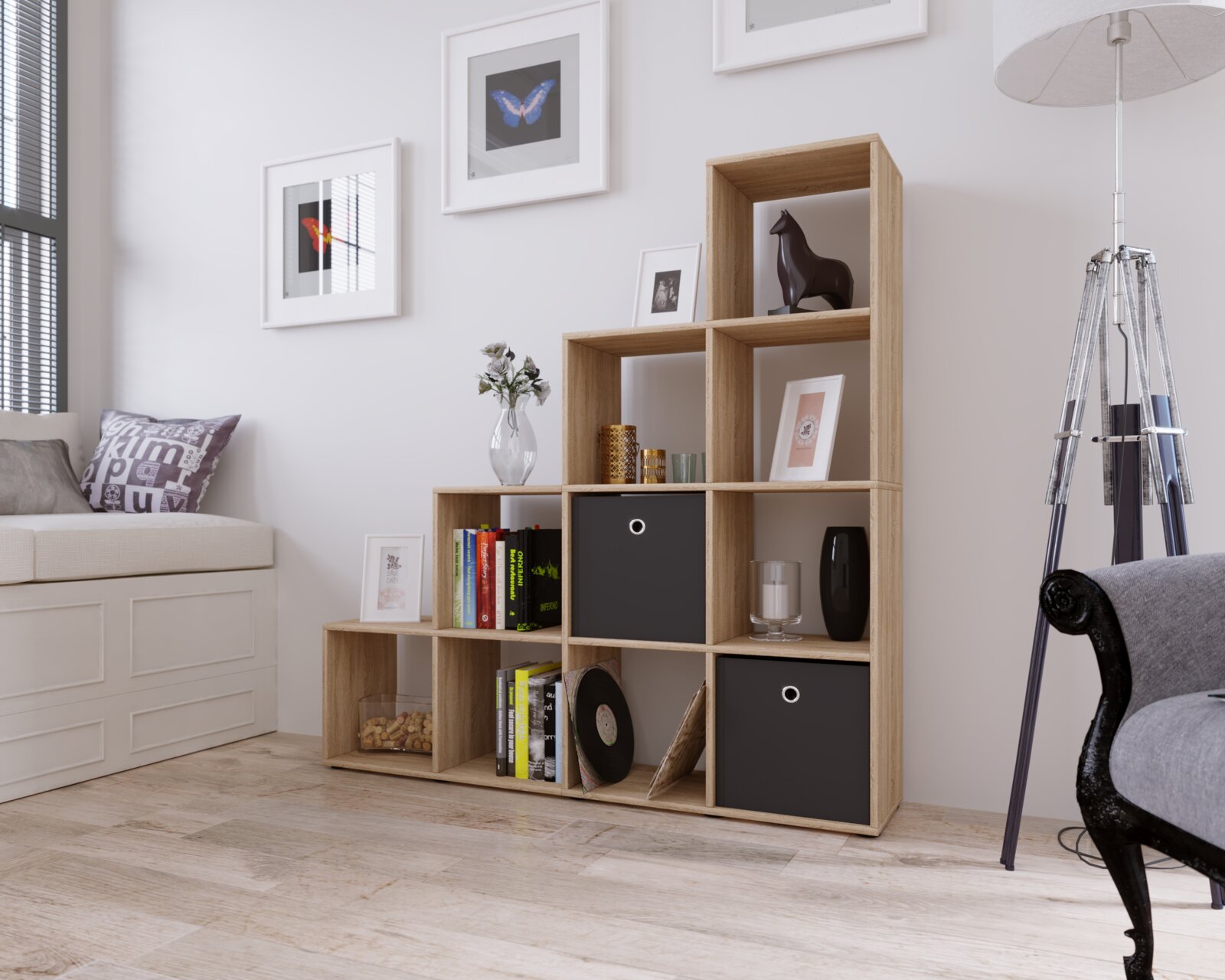 Modulares Stufenregal in Eiche-Optik mit offenen Fächern und zwei schwarzen Aufbewahrungsboxen, dekoriert mit Büchern und Dekoartikeln, in einem hellen Wohnzimmer – Ansicht schräg von vorn.