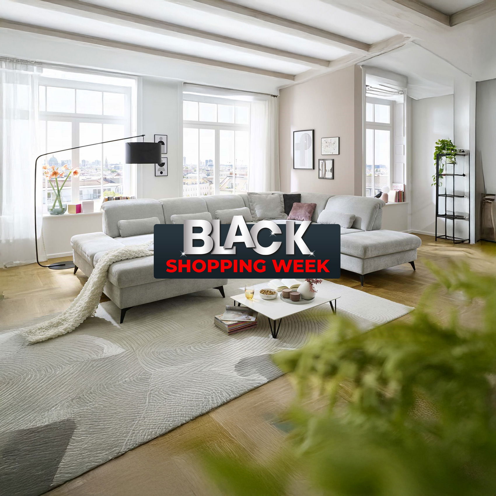 Modernes Wohnzimmer mit heller Eckcouch und großem Fenster, darüber Schriftzug „Black Shopping Week