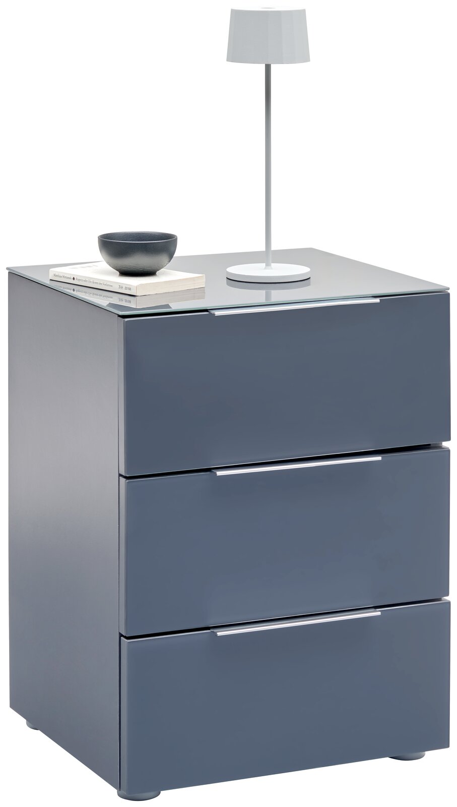 Voleo Nachtkonsole MALIN Moderne Nachtkonsole in Grau mit drei Schubladen, darauf eine weiße Tischlampe und Bücher, seitliche Perspektive