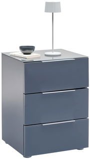 Moderne Nachtkonsole in Grau mit drei Schubladen, darauf eine weiße Tischlampe und Bücher, seitliche Perspektive