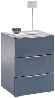 Moderne Nachtkonsole in Grau mit drei Schubladen, darauf eine weiße Tischlampe und Bücher, seitliche Perspektive