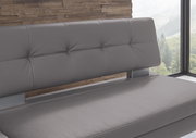 Graue Eckbank mit gepolsterter Rückenlehne, seitliche Perspektive, modernes Design vor einer Holzwand und Fenster mit Ausblick.