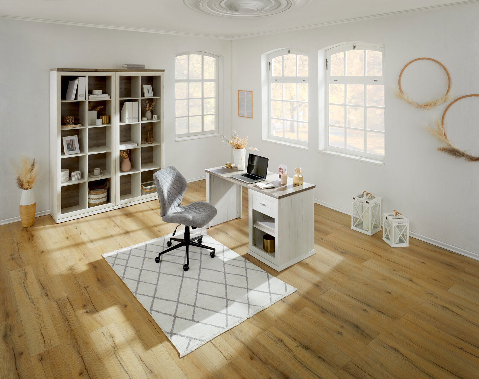 Heller, moderner Schreibtisch in einem stilvoll eingerichteten Raum mit großen Fenstern, einem Bücherregal und einem ergonomischen Stuhl, aus der Vogelperspektive betrachtet.