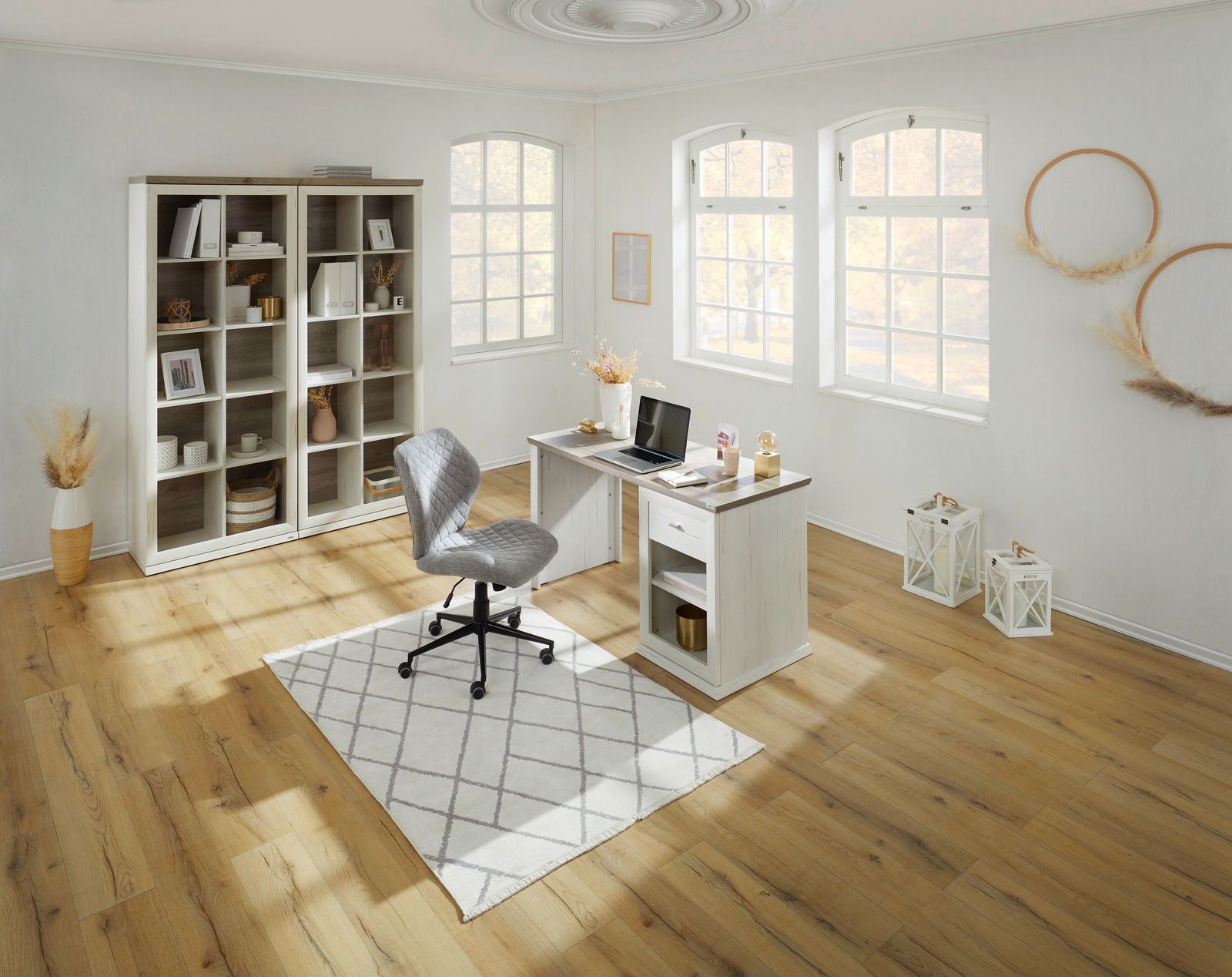 Heller, moderner Schreibtisch in einem stilvoll eingerichteten Raum mit großen Fenstern, einem Bücherregal und einem ergonomischen Stuhl, aus der Vogelperspektive betrachtet.