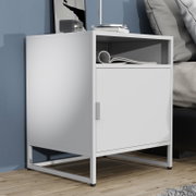Weißer, moderner Nachttisch/Beistellschrank mit offener Ablage und Türfach auf Metallgestell neben einem Bett, schräg von vorne links fotografiert.