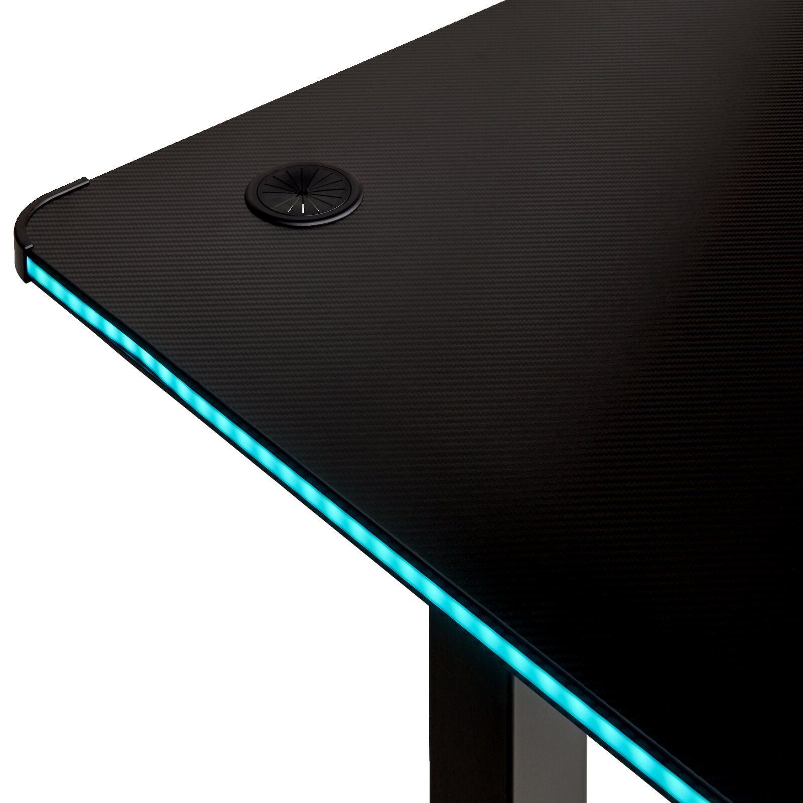 Detailansicht eines schwarzen Gaming-Schreibtischs mit Carbon-Optik, integrierter blauer LED-Kantenbeleuchtung und Kabeldurchlass in der Tischplatte, fotografiert aus schräger Draufsicht.
