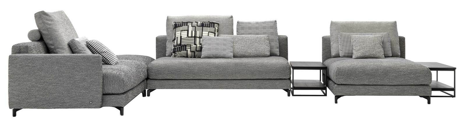 Graue Polsterrundecke mit mehreren Kissen und integrierten Beistelltischen, seitliche Perspektive