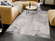 Designer Teppich in einem modernen Wohnzimmer mit beigen Sofas und einem runden Couchtisch, aus der Vogelperspektive betrachtet.