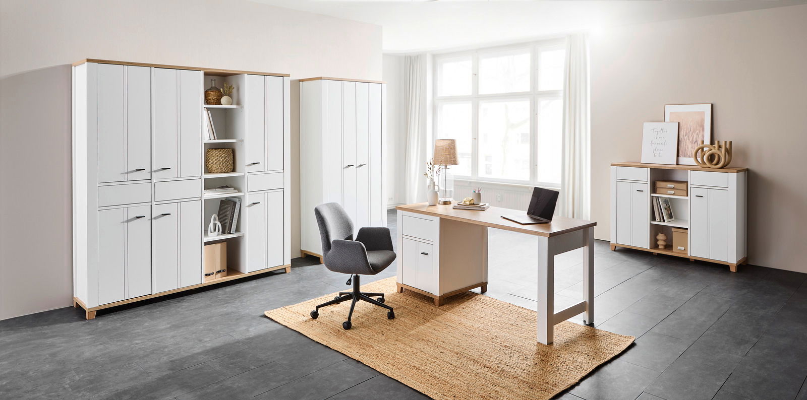 Moderne Büromöbelkombination in heller Umgebung mit Schreibtisch, Drehstuhl und mehreren Schränken, seitliche Perspektive.