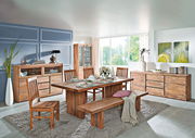 Esszimmer mit Holzmöbeln, darunter ein großer Esstisch, Stühle und eine Bank aus Holz. Die Perspektive zeigt den Raum von der Seite, mit Blick auf den Tisch und die Bank.
