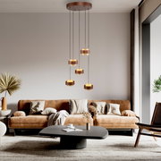 Moderne led-hanglamp met meerdere ronde lichtelementen, hangend boven een stijlvolle woonkamer met een bruine bank en salontafel, gezien vanaf de zijkant.