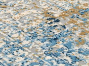 Nahaufnahme eines Designer-Teppichs mit abstraktem Muster in Blau-, Beige- und Grautönen, von oben betrachtet.